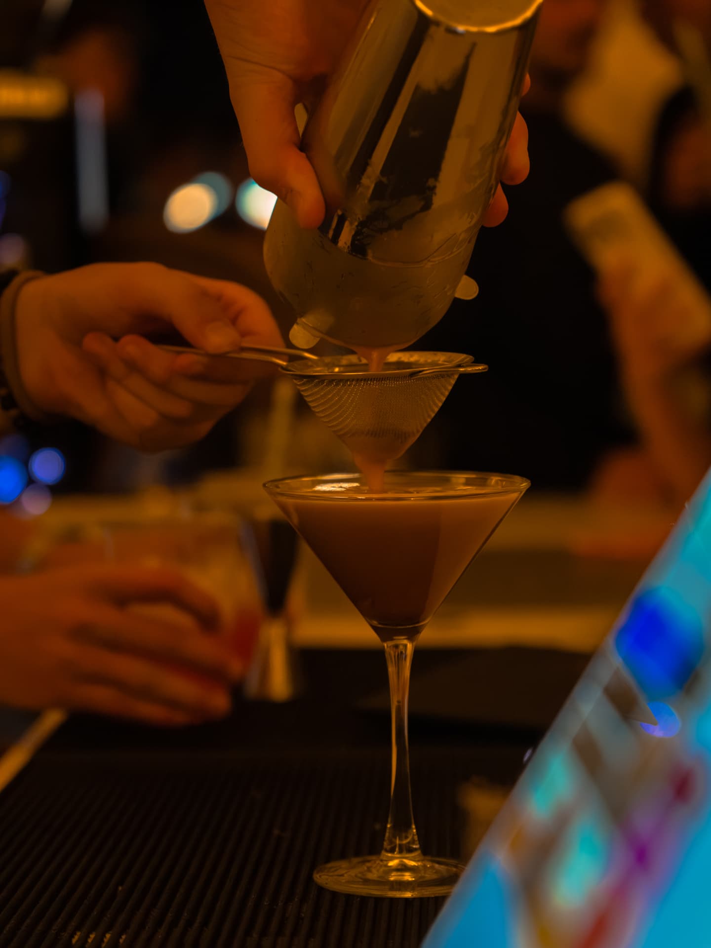 A GetBarred bartender pouring a cocktail into a martini glass at an event